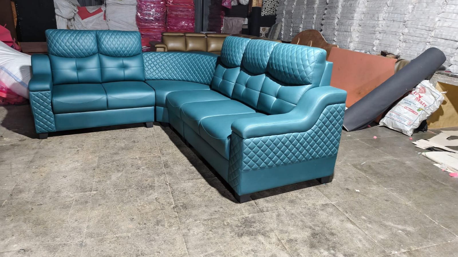 Teal leather quilted corner sofa set in showroom